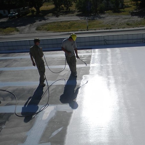 Commercial roofer applies coating.